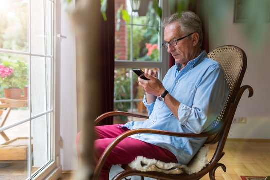 Senior Man Using Mobile Phone At Home