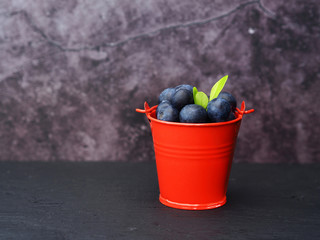  Blueberries in red bucket on black wooden. 