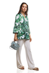 Full shot of a young chestnut European lady dressed in white casual trousers, loose jacket with...