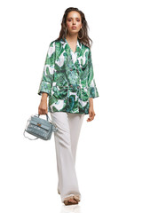 Full shot of a young chestnut European lady dressed in white casual trousers, loose jacket with...