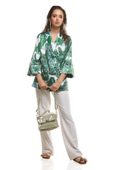Full shot of a young chestnut European lady dressed in white casual trousers, loose jacket with...