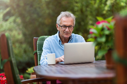 Senior man working on laptop in the garden