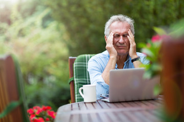 Obraz premium Senior man looking stressed while working on laptop 