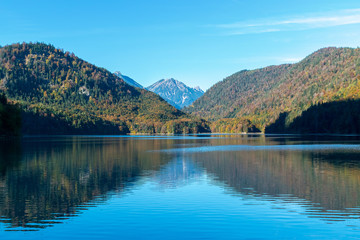 Fototapeta na wymiar Symmetric reflection of Alps and the forest on shores in the water surface in the lake in autumn