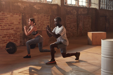 Sport couple doing leg lunge exercise workout at gym - obrazy, fototapety, plakaty