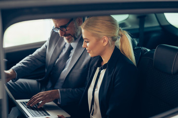 business people using laptop computer at backseat of car
