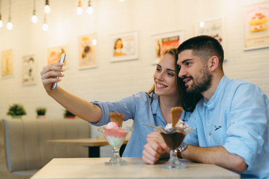 couple taking picture with smartphone while eating ice cream