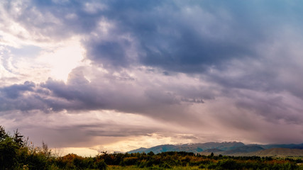 Fototapeta premium Panorama of a mountain valley in the summer. Amazing nature, mountains lit by sunset, summer in the mountains. Travel, tourism, beautiful background, picture of nature