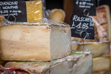 A cheese stall in a market, with a shallow depth of field