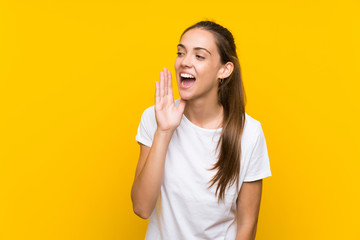 Young woman over isolated yellow background shouting with mouth wide open