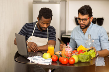 Fototapeta na wymiar Two men using laptop in kitchen