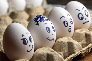 Lovely eggs in cardboard box. Eggs with emotions. White eggs in cardboard box with different faces painted on them. Boys and girl