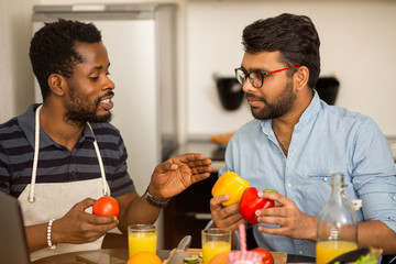 Two men using laptop in kitchen