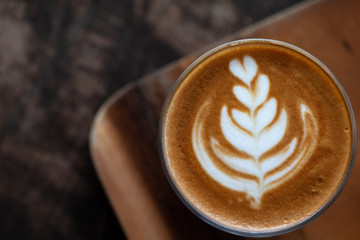 A glass cup of Latte art coffee on wooden desk