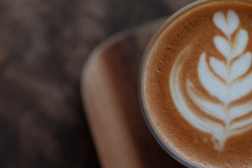 A glass cup of Latte art coffee on wooden desk