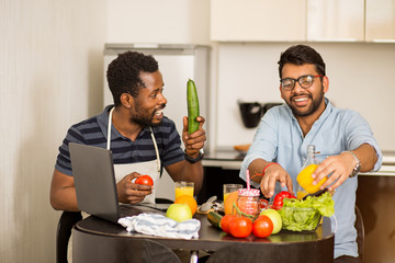 Two man using laptop in kitchen