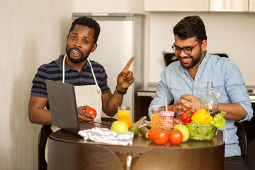 Two man using laptop in kitchen
