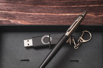pen and USB flash drive in a gift box on a wooden background