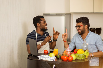 Two men using laptop in kitchen