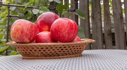 Red apples in a wicker basket on a burlap.
