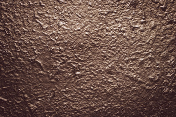 Brown rough concrete painted wall. Grunge background. Reflective on raggy surface. Dark texture with metallic gloss. Shiny stucco, paint. Abstract architecture uneven backgrounds.