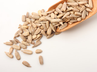 High angle view of natural shelled organic sunflower seeds on wooden spoon isolated on white background. It often eaten as a snack.  The seeds contain vitamin E. Food, snack concept. With copy space.