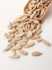 High angle view of natural shelled organic sunflower seeds on wooden spoon isolated on white background. It often eaten as a snack.  The seeds contain vitamin E. Food, snack concept. With copy space.