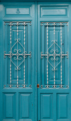 Turquoise wooden front door with white bars