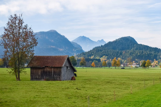Old wooden barn in a meadow in the Alps in autumn with mountains