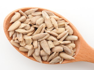 Top view of natural shelled organic sunflower seeds on wooden spoon isolated on white background. It often eaten as a snack.  The seeds contain vitamin E. Food and snack concept.