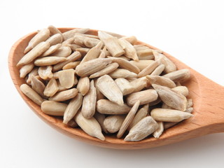 High angle view of natural shelled organic sunflower seeds on wooden spoon isolated on white background. It often eaten as a snack.  The seeds contain vitamin E. Food and snack concept.