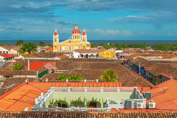 Urban skyline of Granada city at sunset with its spanish colonial architecture, colorful cathedral and beautiful rooftops with the Nicaragua Lake in the background, Nicaragua, Central America. - obrazy, fototapety, plakaty