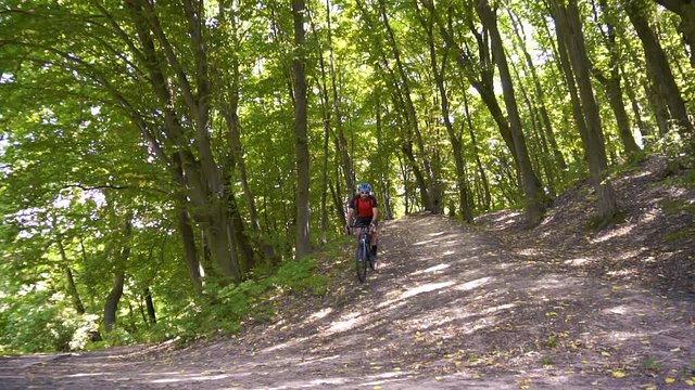 Young man biking on a forest road in a sammer day. active recreation, sport, healthy lifestyle. slow motion