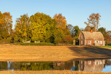 Obraz premium Old cottage and a passage grave in rural landscape at autum