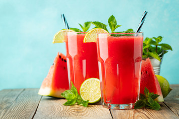 Watermelon slushie with lime and mint, summer refreshing drink in tall glasses on a light blue...