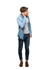 Fototapeta premium A full-length shot of a Handsome young man listening to something by putting hand on the ear over isolated white background