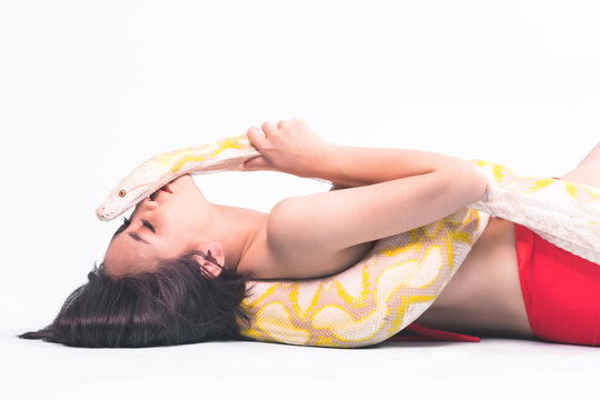 Snake, woman isolated. Asian woman in bikini holding yellow python. Kissing it. Strange woman fashion concept.