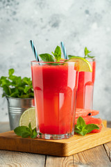 Watermelon slushie with lime and mint, summer refreshing drink in tall glasses on a light blue background. Sweet cold smoothie