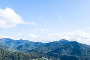 landscape of the ridge covered with green trees and view a valley flooded with sunlight ,pasture, with dense clouds in the sky. summer day in the mountains of the Altai