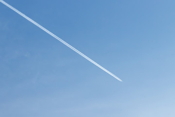 White plane flying high in blue sky