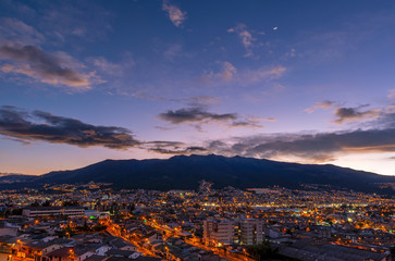 Cityscape of Quito city at sunset with the mighty peaks of the Pichincha volcano, Andes mountains, Ecuador.