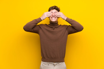 Fototapeta premium Handsome young man over isolated yellow background covering eyes by hands