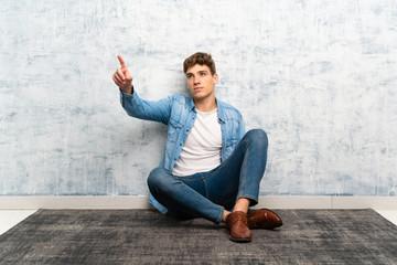 Handsome young man sitting on the floor touching on transparent screen