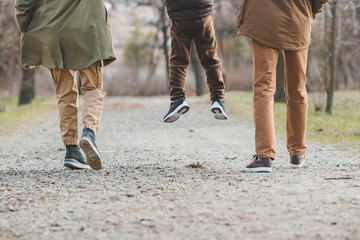young beautiful family walking holding hands by city park