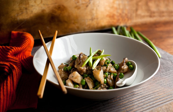 Close up of stir fried cod with mushrooms and peas served in bowl