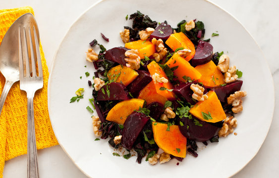 Overhead view of roasted beet and winter squash salad with walnuts on plate