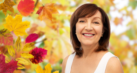 beauty and old people concept - portrait of smiling senior woman over autumn leaves and nature...