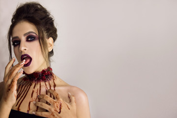 young sexy brunette girl with halloween bloody makeup is standing and looking straight with fingers...