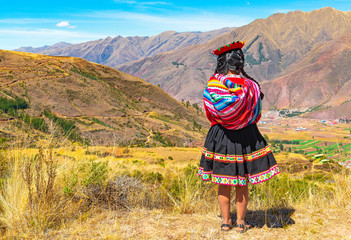 An indigenous Peruvian Quechua lady looking at the Andes Mountain Range in the Inca ruin of Tipon in the region of Cusco, Peru. Square format. - obrazy, fototapety, plakaty