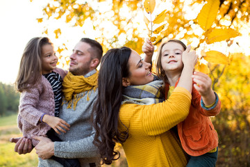A portrait of young family with two small children in autumn nature.